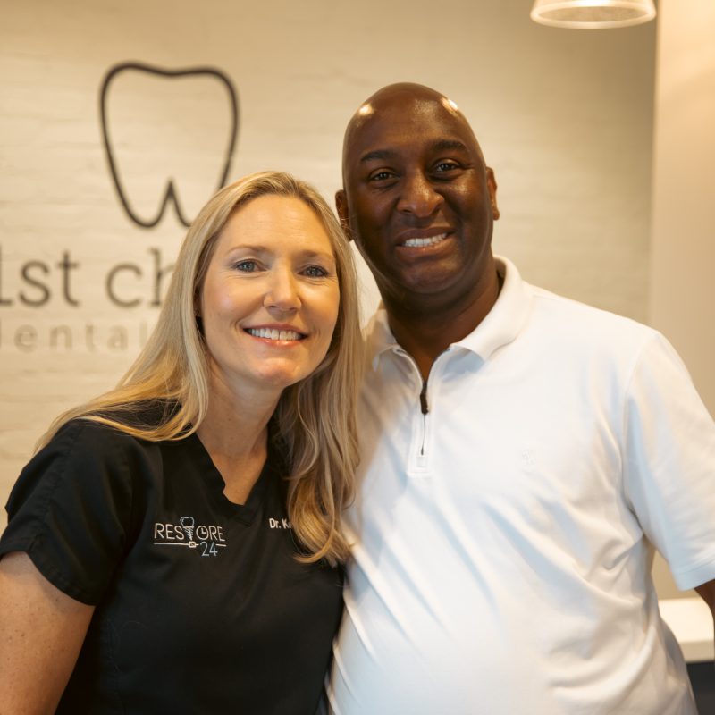 Dr. Kelly Vaughn standing with a patient in front of the 1st Choice Dental Center logo