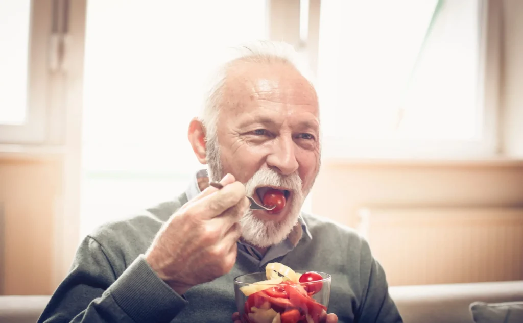 man with implant denture eats food